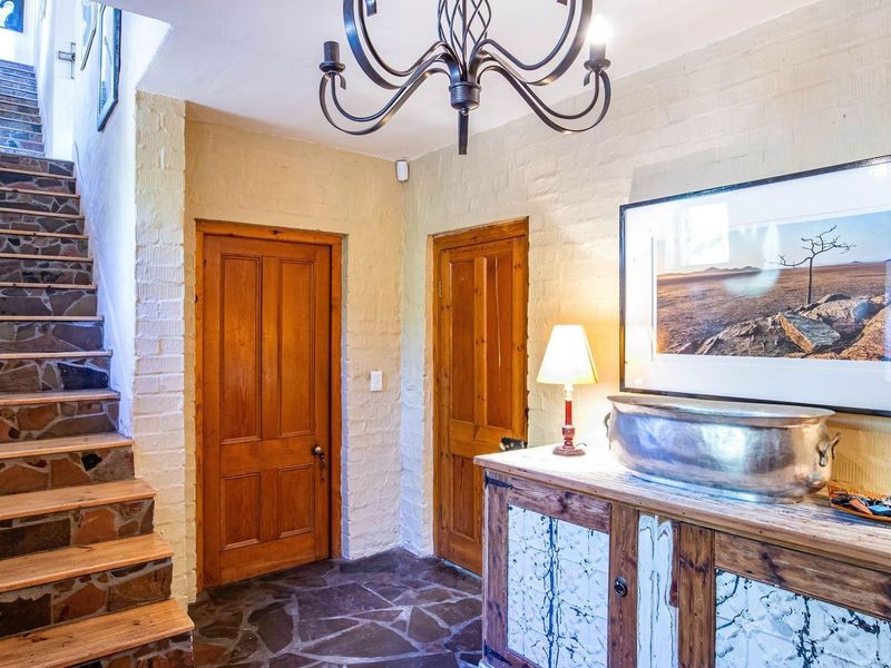 Welcoming entrance hall featuring rustic stone flooring, exposed brick walls, and a characterful staircase with a wooden handrail and stone treads.