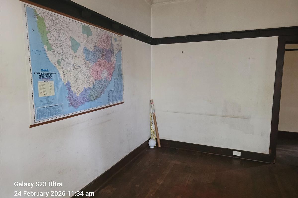 An empty room featuring original timber flooring, dark wood picture rails, and decorative ceiling cornicing, requiring cosmetic updates to restore its character.