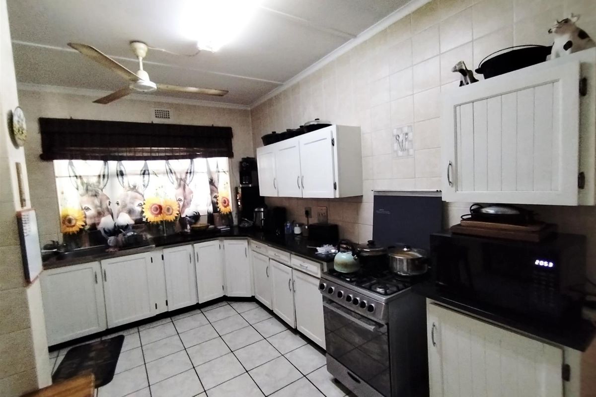 Functional kitchen featuring white cabinetry, dark granite countertops, gas stove, tiled backsplash, and tiled flooring.
