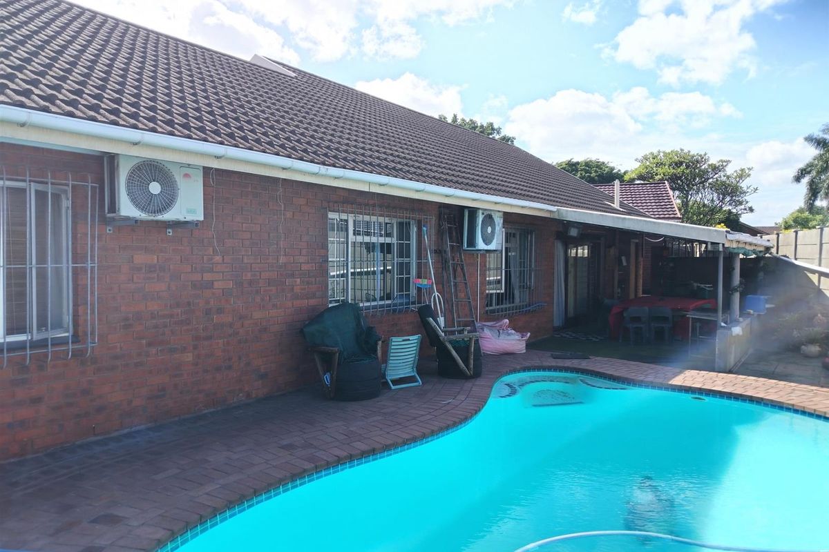 Rear exterior view of the house featuring a swimming pool, paved patio area, and brick facade with mounted air conditioning units.