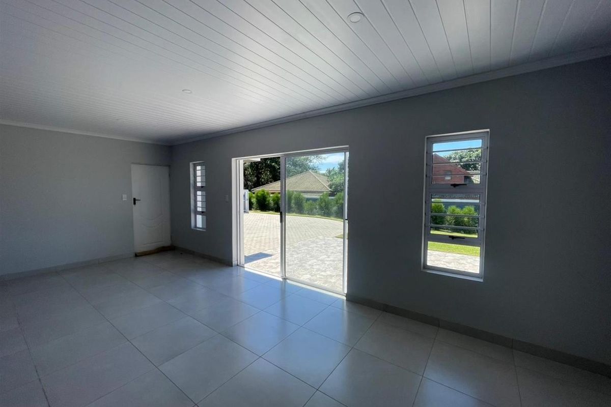 A bright, empty living area featuring neutral tiled floors, modern recessed lighting, and large sliding glass doors providing access to the exterior.