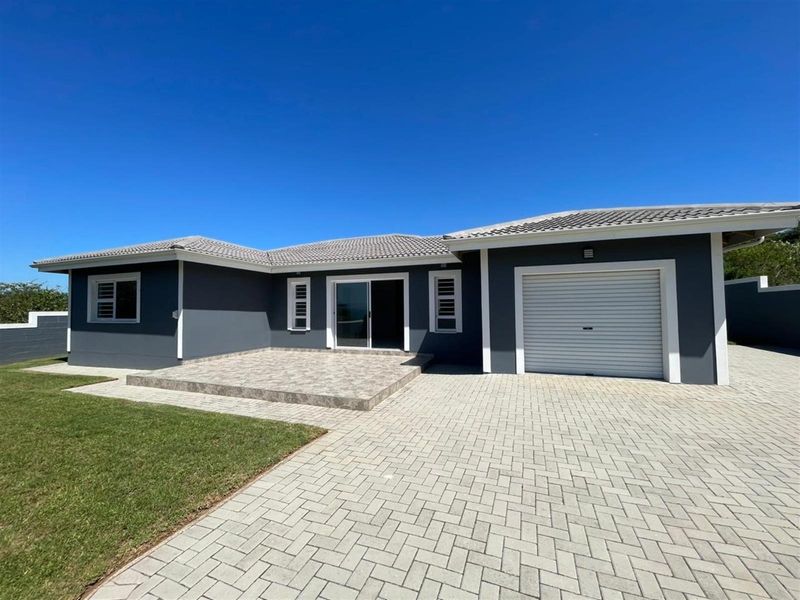 A well-maintained single-story home featuring a paved driveway, attached garage, tiled patio area, and modern grey exterior finish.