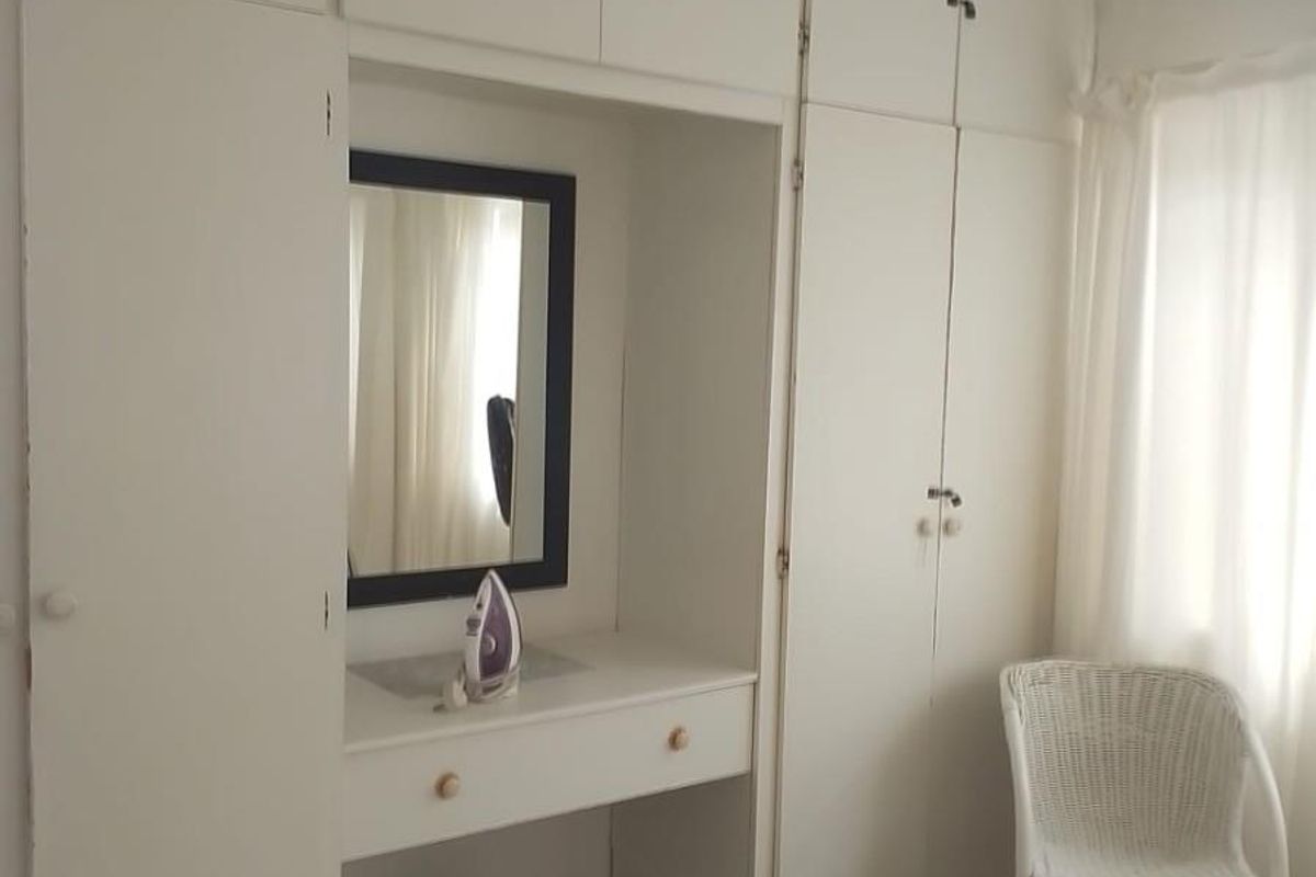Bedroom featuring extensive built-in white cabinetry with integrated vanity and tiled flooring.