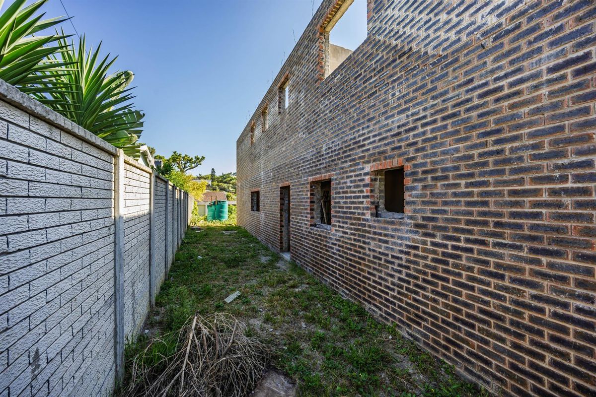 Side view of a property under construction, featuring exposed brick walls and an unfinished exterior structure.
