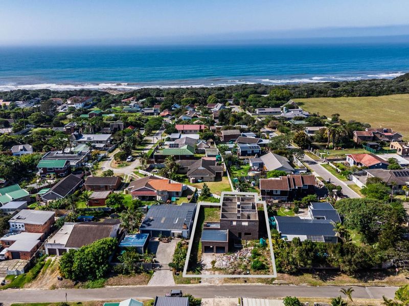 Aerial view of a coastal residential property under construction, highlighting the building footprint and surrounding neighborhood proximity to the ocean.