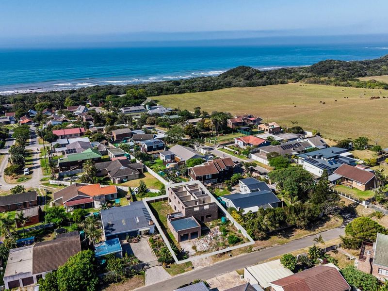 Aerial view of a coastal residential neighborhood featuring a property currently under construction with exposed brick walls and unfinished structural elements.