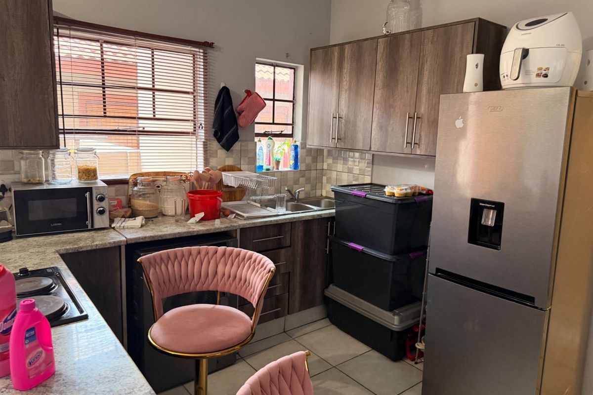 A functional kitchen featuring laminate cabinetry, granite countertops, a stainless steel double sink, and ceramic tile flooring with a window for natural light.