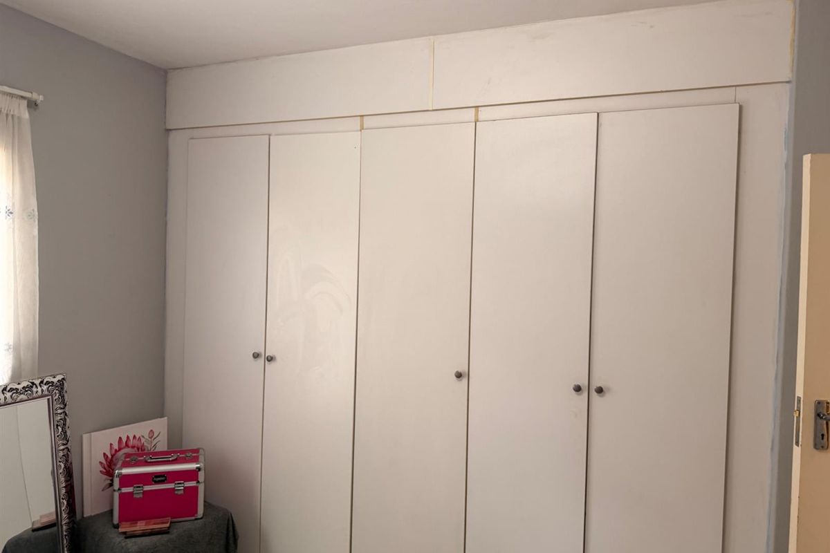 A bedroom featuring floor-to-ceiling built-in cupboards with white doors and a bulkhead finish.