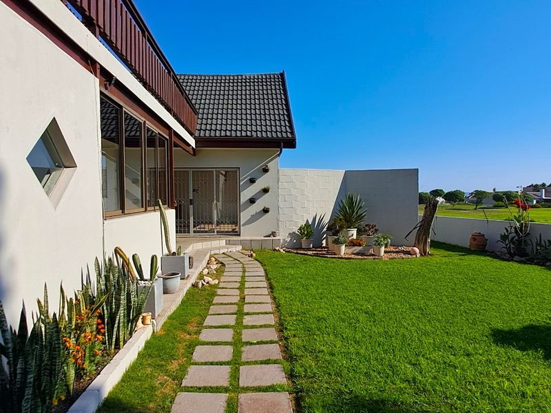 A well-maintained rear garden featuring a paved walkway, manicured lawn, and perimeter wall, providing a private outdoor space.