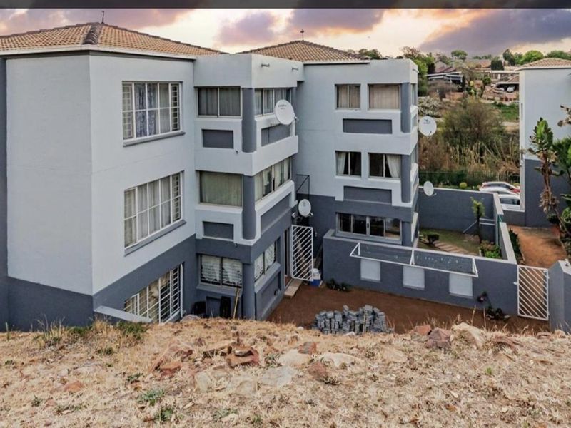 An elevated view of the apartment complex exterior, featuring multi-story residential blocks with grey and white facade finishes and surrounding grounds.
