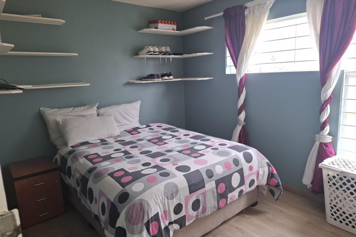 A bedroom featuring light wood-look flooring, blue-painted walls, and built-in floating shelving units.