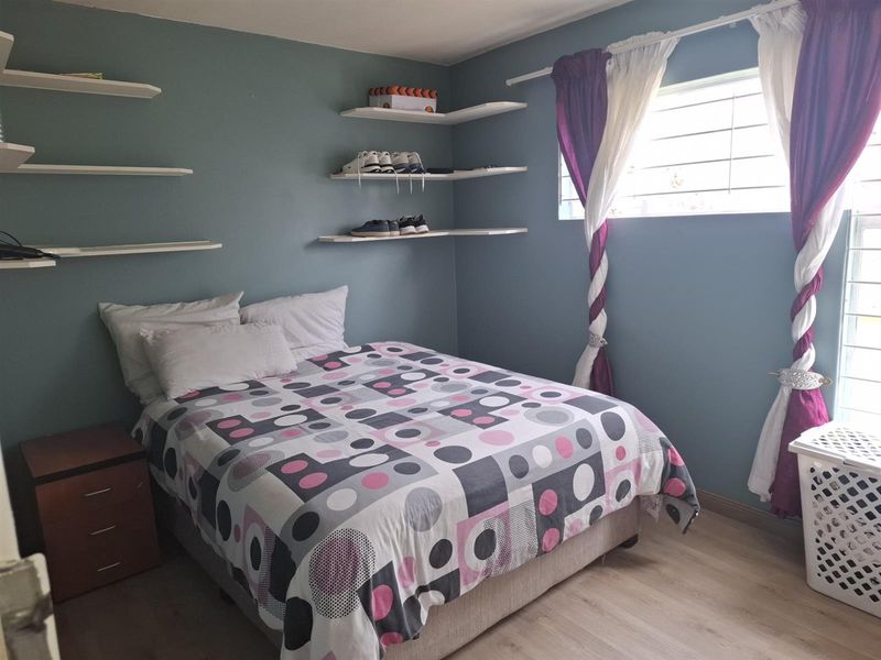 A bedroom featuring light wood-look flooring, blue-painted walls, and built-in floating shelving units.