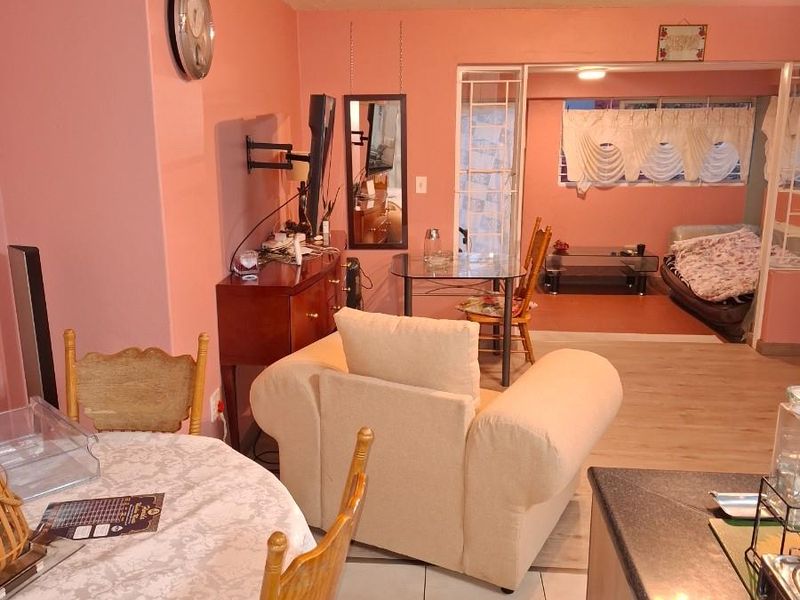 Open plan living and dining area featuring tiled flooring and a connected secondary living space with large windows.