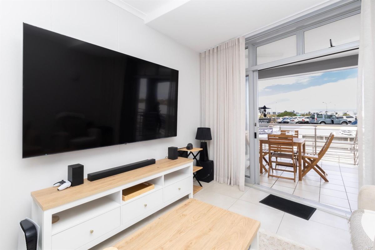 Bright living room featuring tiled flooring and a large sliding glass door providing seamless access to the outdoor balcony area.
