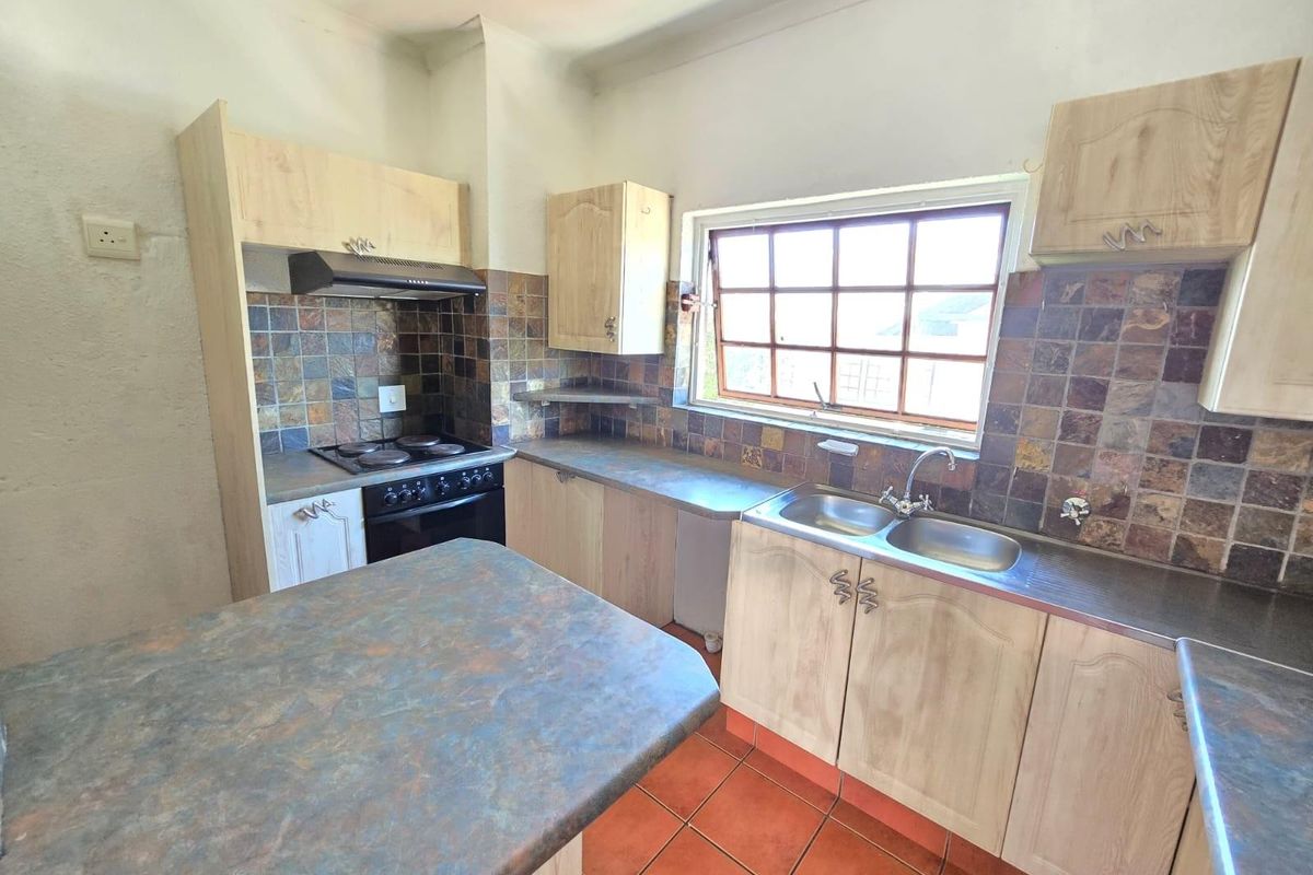 A functional kitchen featuring light wood-look cabinetry, a double stainless steel sink, a built-in stove with extractor fan, and a tiled backsplash.