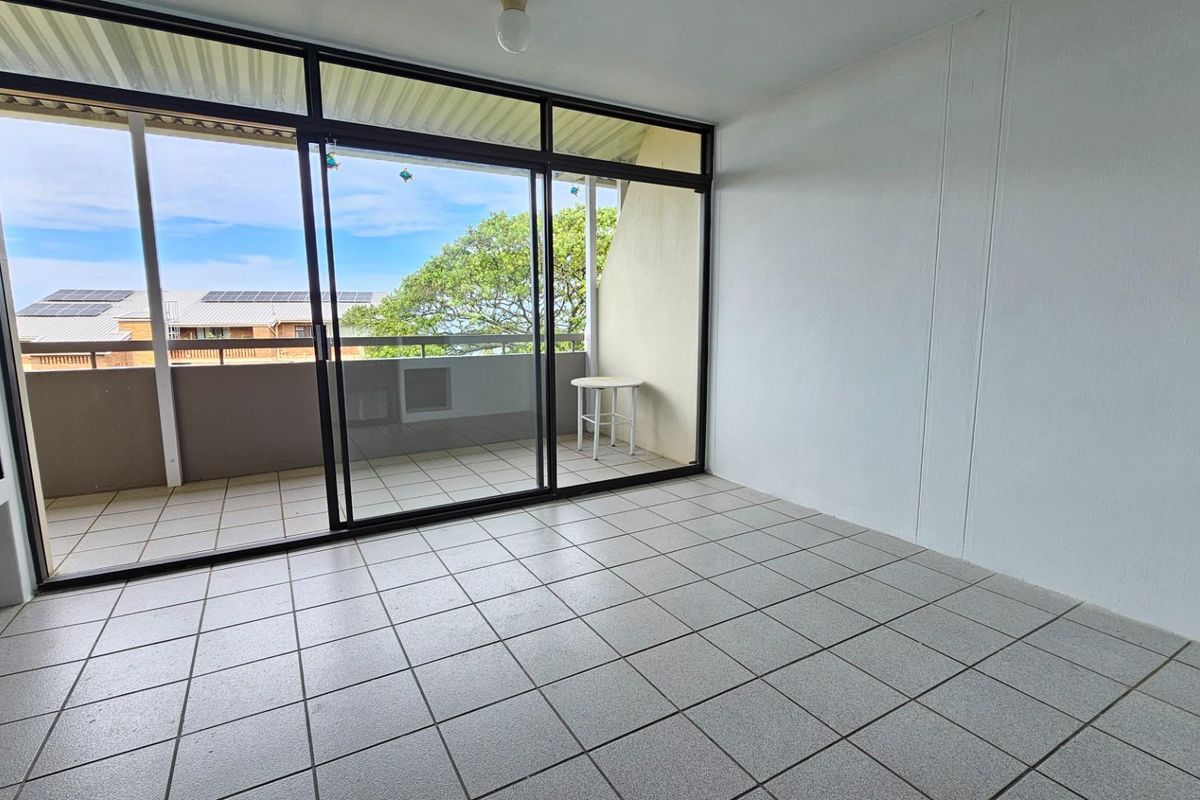 An empty living room featuring tiled flooring, a built-in fireplace, and large sliding glass doors leading to an outdoor balcony area.