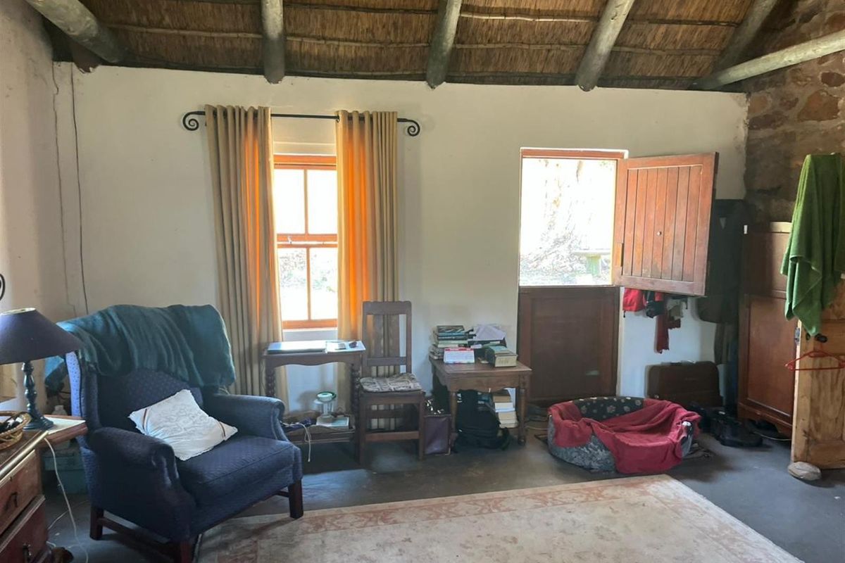 Rustic living area featuring a traditional exposed thatch roof, timber beams, stone wall accents, and a stable-style door leading to the exterior.