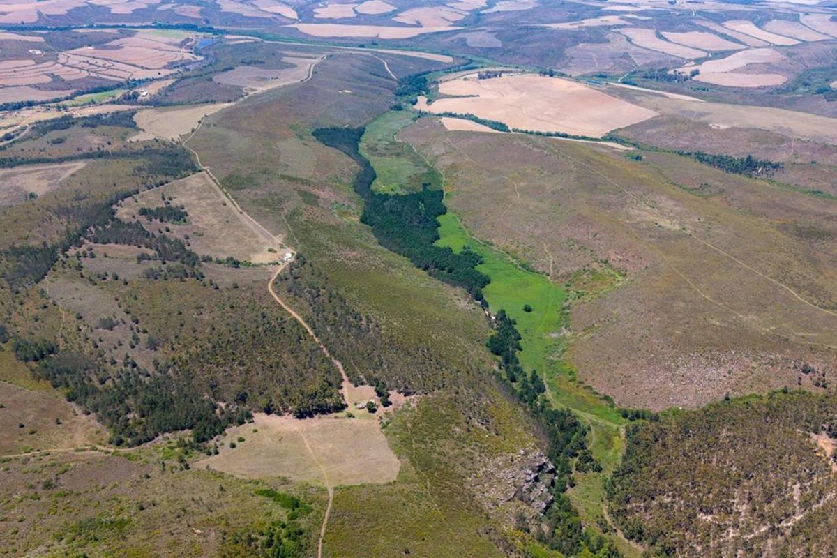 An expansive aerial view of the farm property, showcasing the vast landscape, natural terrain, and surrounding agricultural fields.