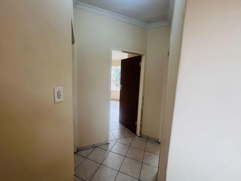 A functional interior hallway featuring tiled flooring and access to adjacent rooms through standard doorways.