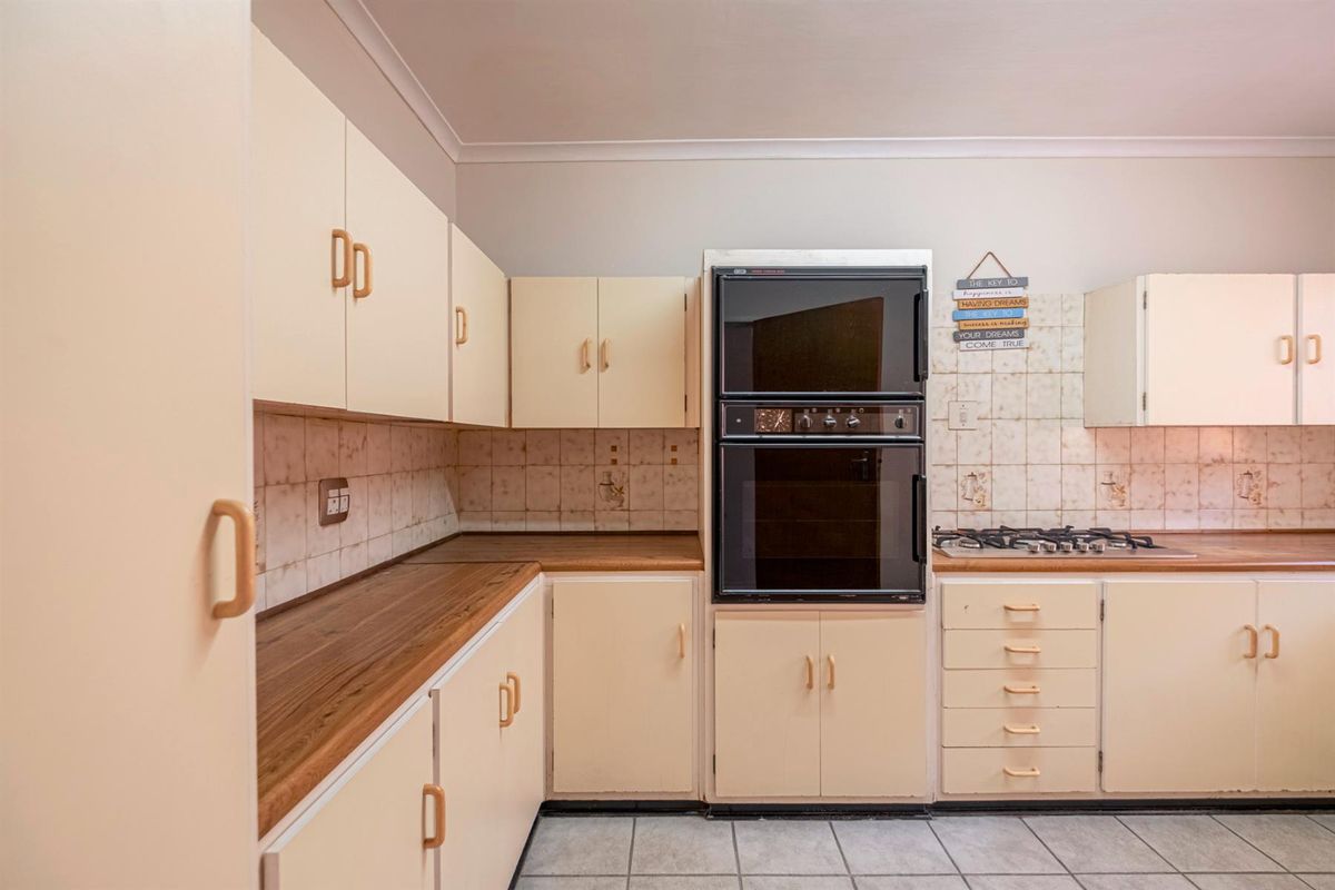 A functional kitchen featuring built-in cabinetry, a double wall oven, gas hob, and tiled flooring with a neutral backsplash.