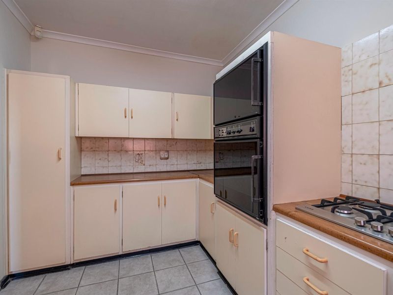 A functional kitchen featuring built-in cabinetry, a gas hob, and a wall-mounted oven, offering a practical layout with tiled flooring and backsplash.