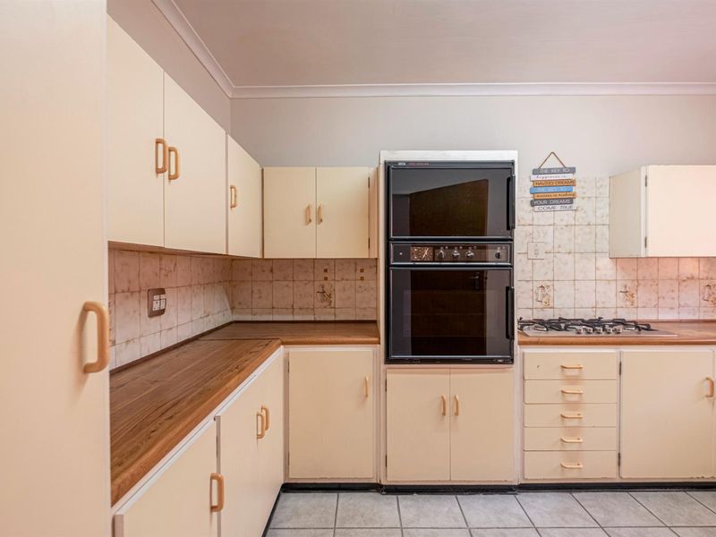 A functional kitchen featuring built-in cabinetry, a double wall oven, gas hob, and tiled flooring with a neutral backsplash.