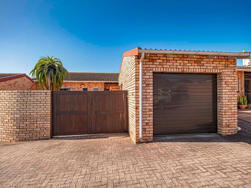 Front exterior view of the townhouse featuring a face-brick facade, a single garage with a sectional door, and a private gated entrance.