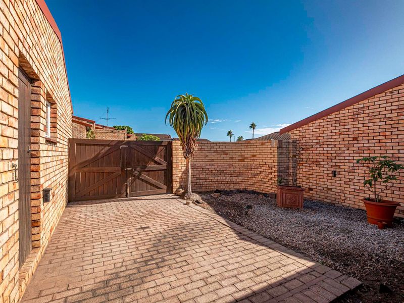 A private rear courtyard featuring paved flooring, a secure wooden gate, and perimeter brick walls, offering a low-maintenance outdoor space.