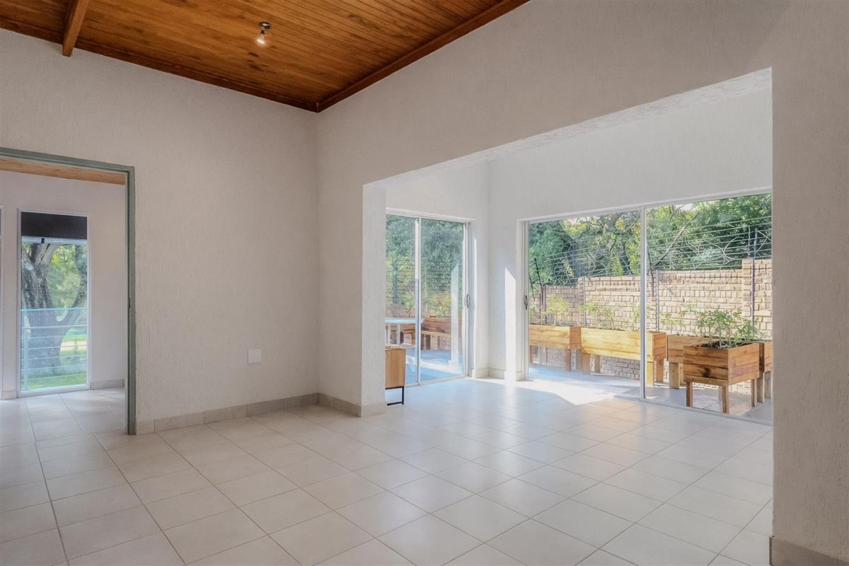 Spacious living area featuring tiled flooring, a warm timber-clad ceiling, and large sliding glass doors that open onto a private patio.