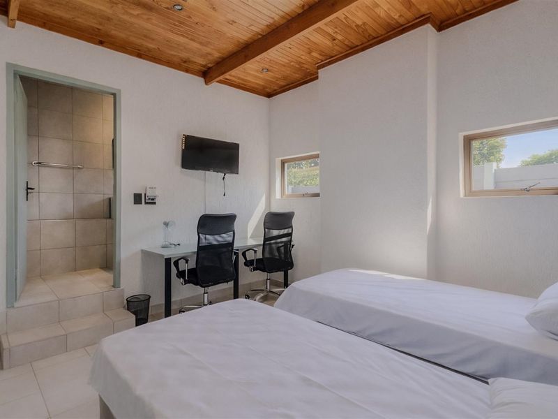 A bedroom featuring a timber-clad ceiling, tiled flooring, and an en-suite bathroom with a raised entry step.