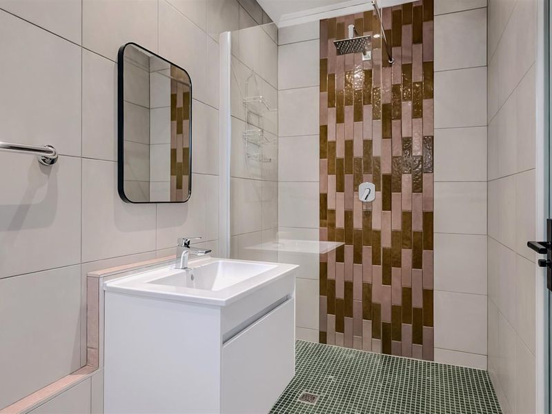 Modern bathroom featuring a walk-in shower with decorative accent tiling, a contemporary vanity unit, and a wall-mounted mirror.