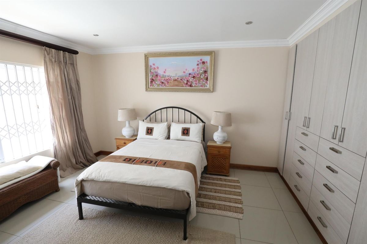 A well-maintained bedroom featuring built-in wardrobes, tiled flooring, and recessed ceiling lighting, offering a clean and functional living space.
