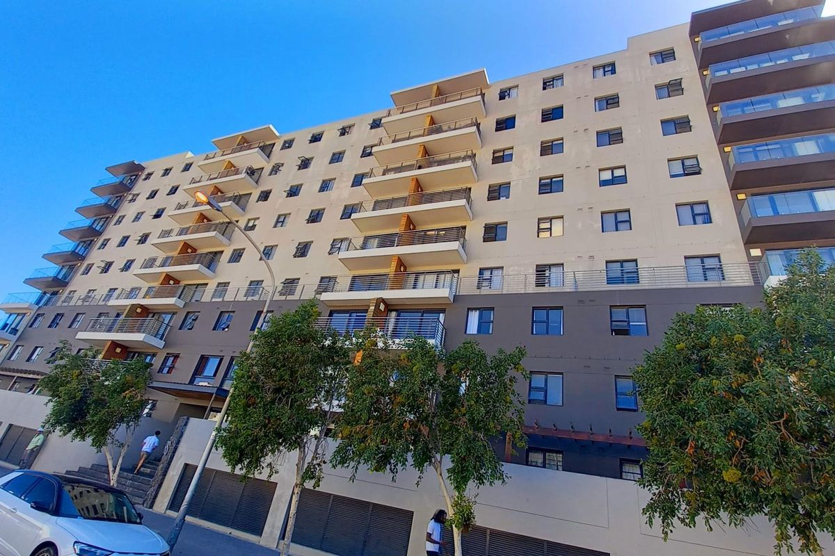 A multi-story apartment building facade featuring multiple balconies with glass balustrades and a modern exterior design.