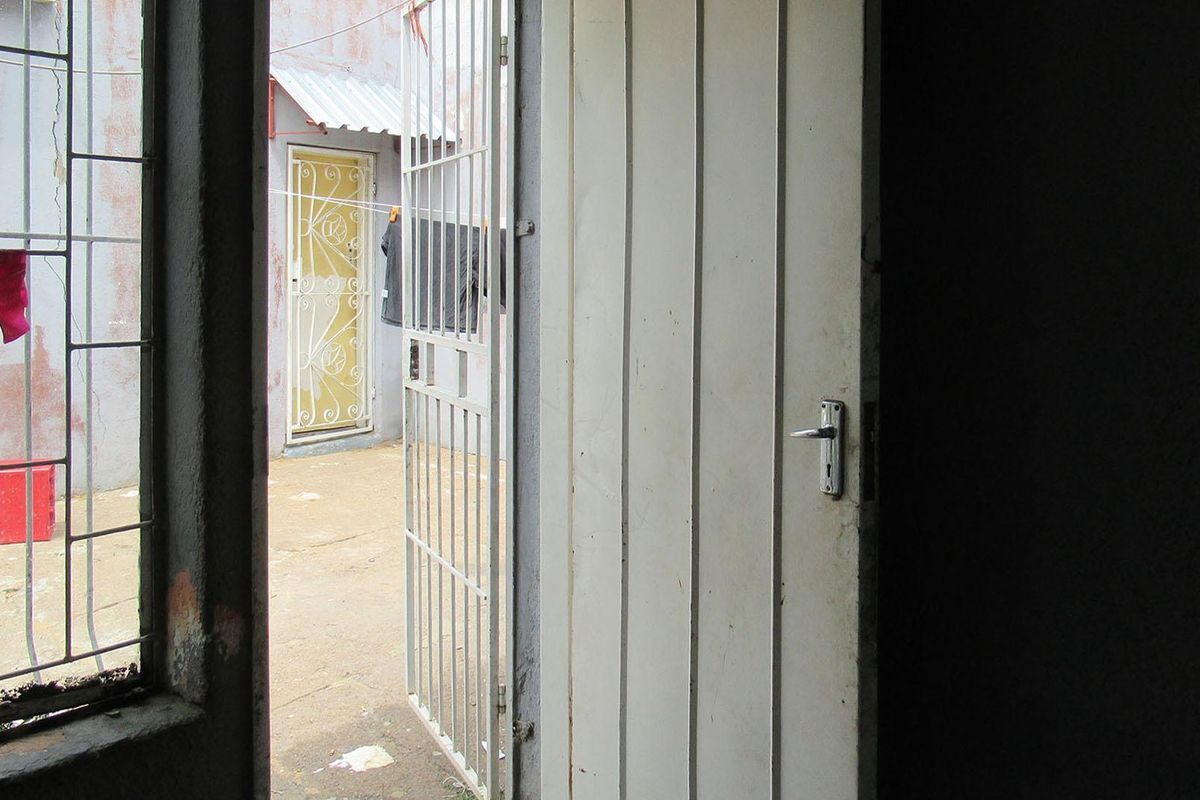 View from an interior space looking out towards a rear courtyard area featuring security gates and a paved outdoor surface.