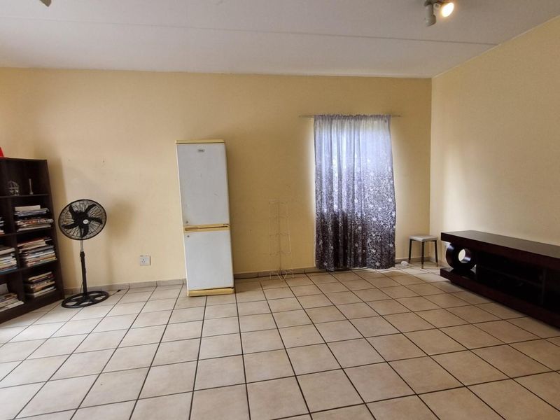 A spacious living room featuring neutral wall paint and tiled flooring, providing a blank canvas for personalized interior design and furniture arrangement.