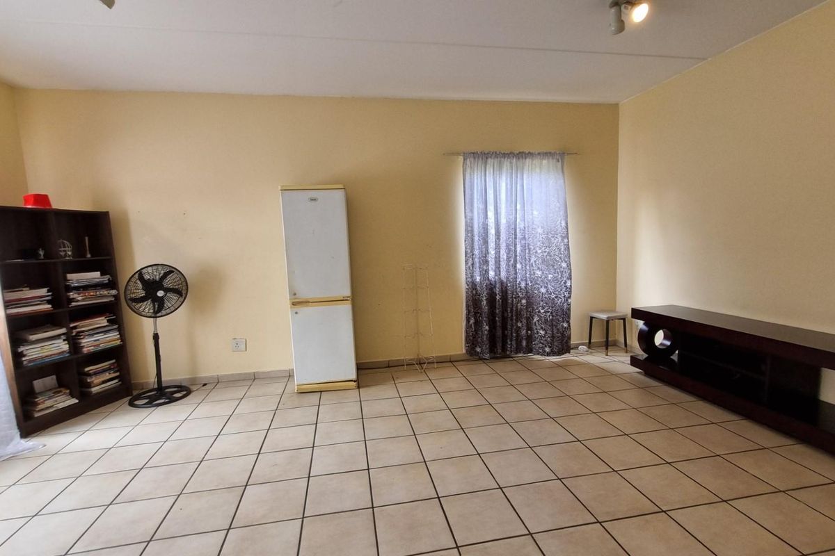 A spacious living room featuring neutral wall paint and tiled flooring, providing a blank canvas for personalized interior design and furniture arrangement.