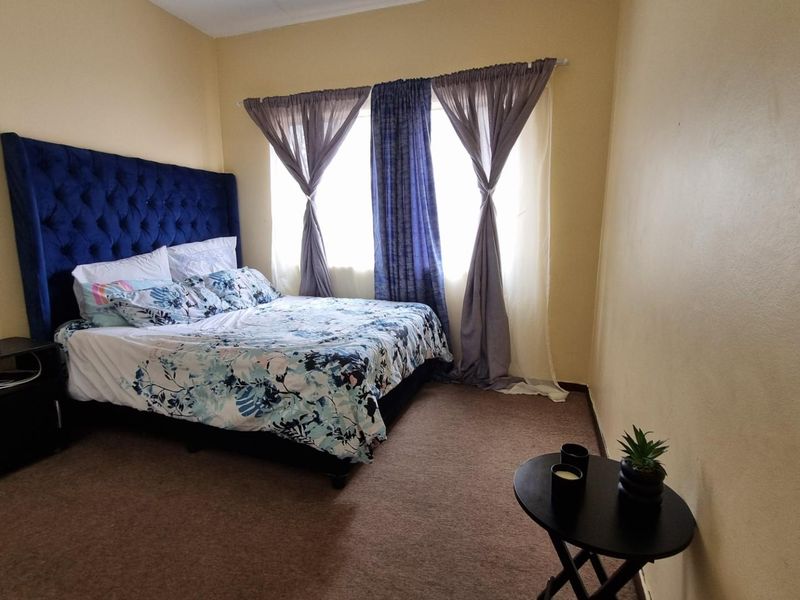 A bedroom featuring carpeted flooring and a window with installed curtain rods.