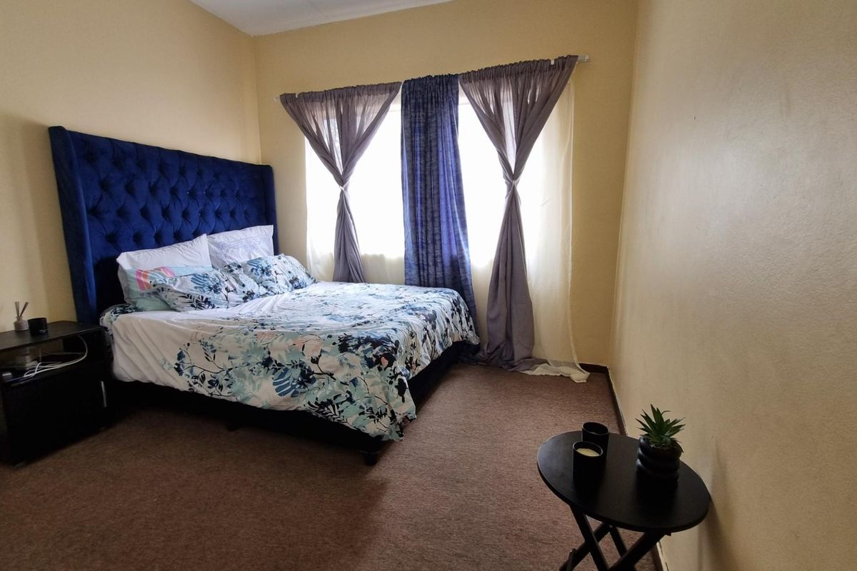 A bedroom featuring carpeted flooring and a window with installed curtain rods.