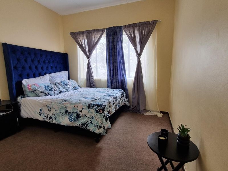 A standard bedroom featuring carpeted flooring and a window with installed curtain rails.