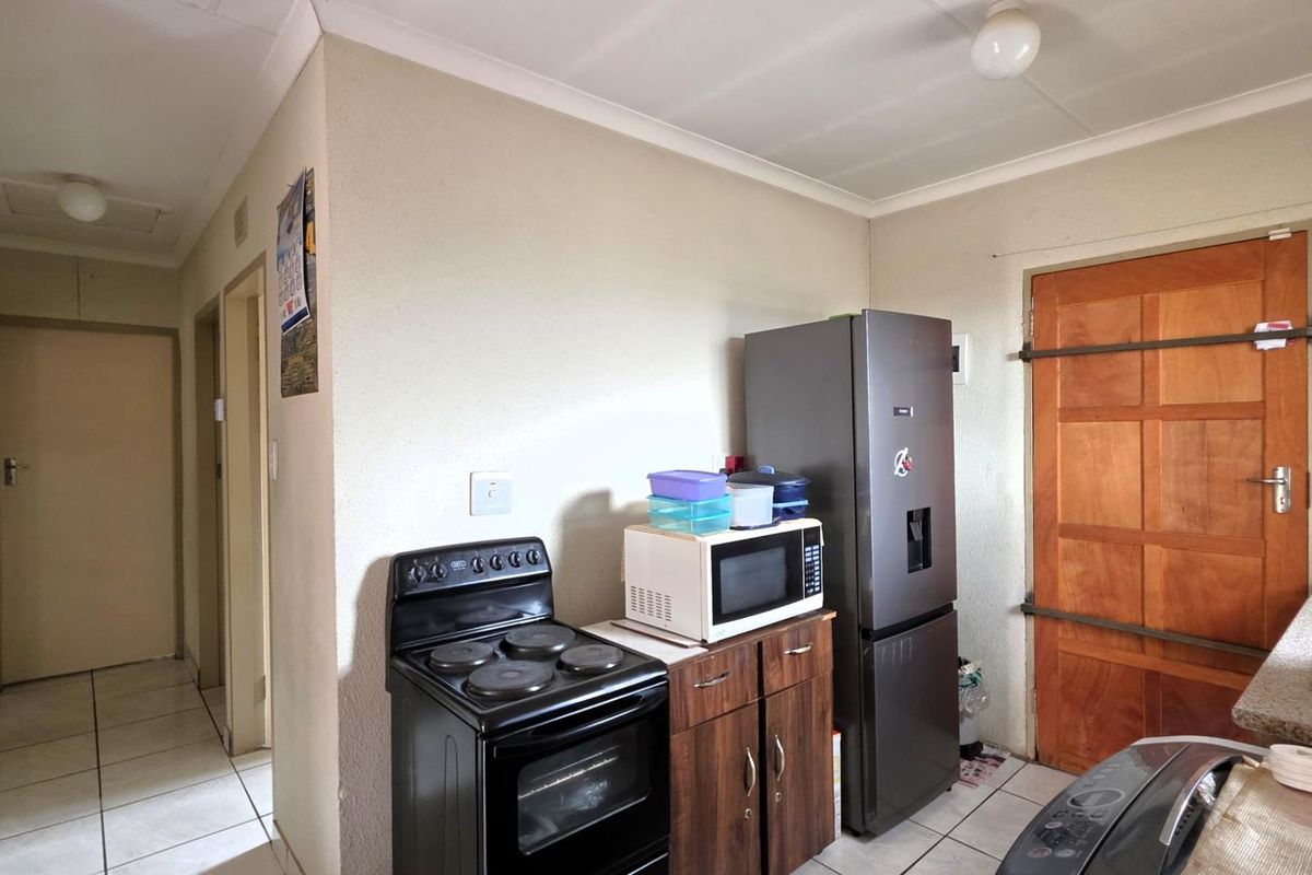 A functional kitchen area featuring tiled flooring, built-in cabinetry, and space for essential appliances, providing a practical layout for daily meal preparation.