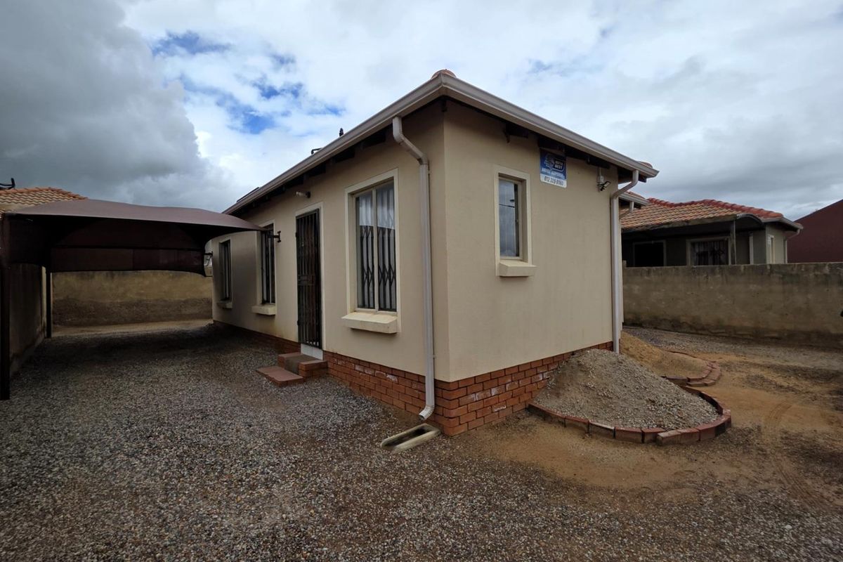 Exterior view of a detached house featuring a carport, brick base detailing, and security bars on windows and doors.