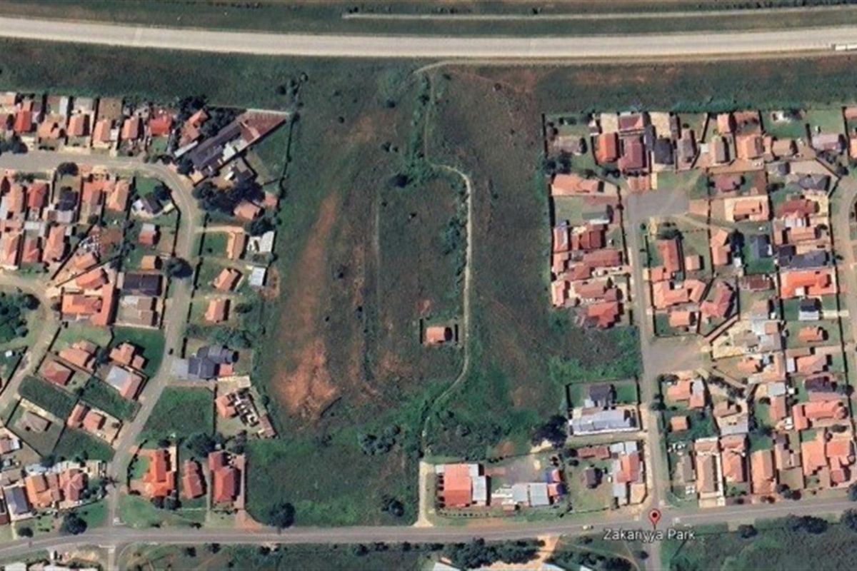 Aerial view of a vacant commercial land plot situated within a residential neighborhood, offering potential for future development.