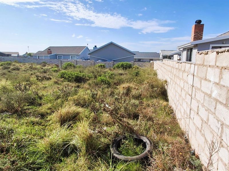 A vacant residential plot featuring overgrown natural vegetation and a perimeter concrete block boundary wall in a suburban neighborhood setting.