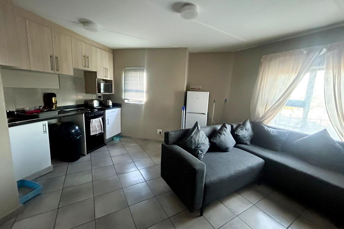 Open plan living area featuring a compact kitchen with built-in cabinetry and tiled flooring throughout.