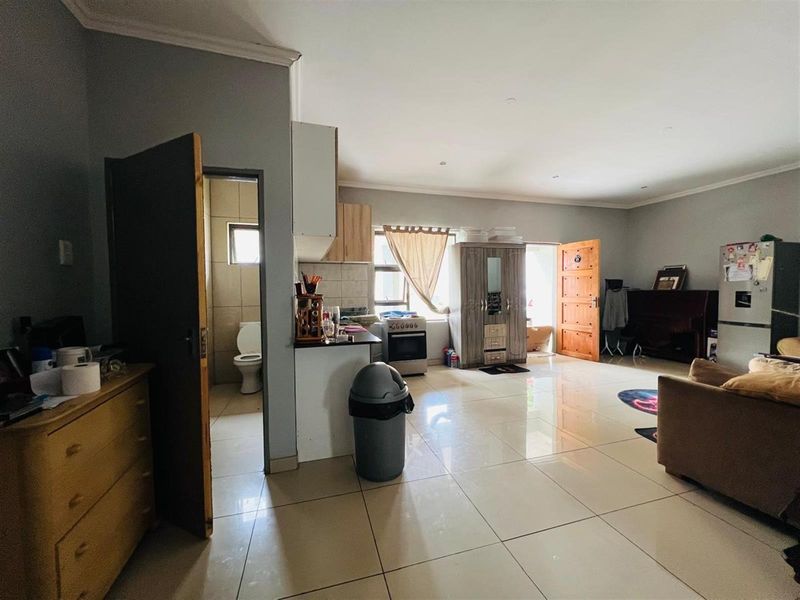 Open plan living area featuring tiled flooring, a compact kitchen corner, and direct access to an adjacent bathroom.