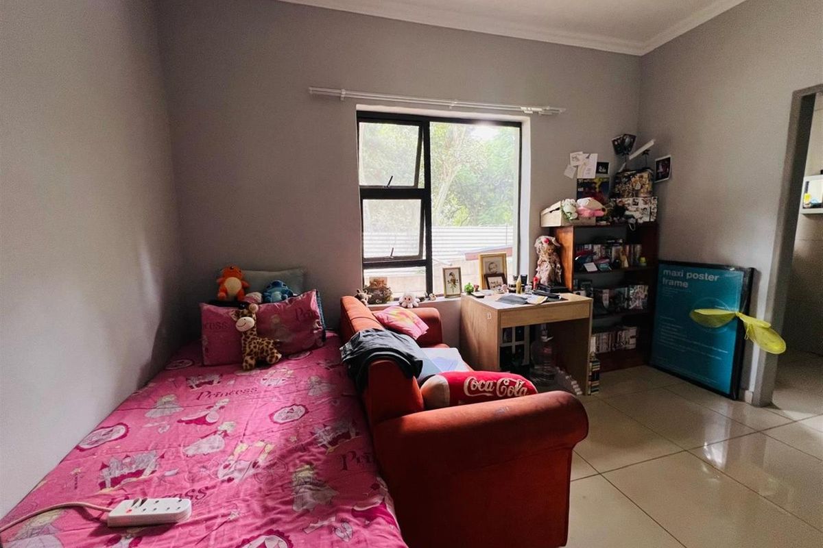 A bedroom featuring tiled flooring, neutral wall paint, and a window providing natural light.