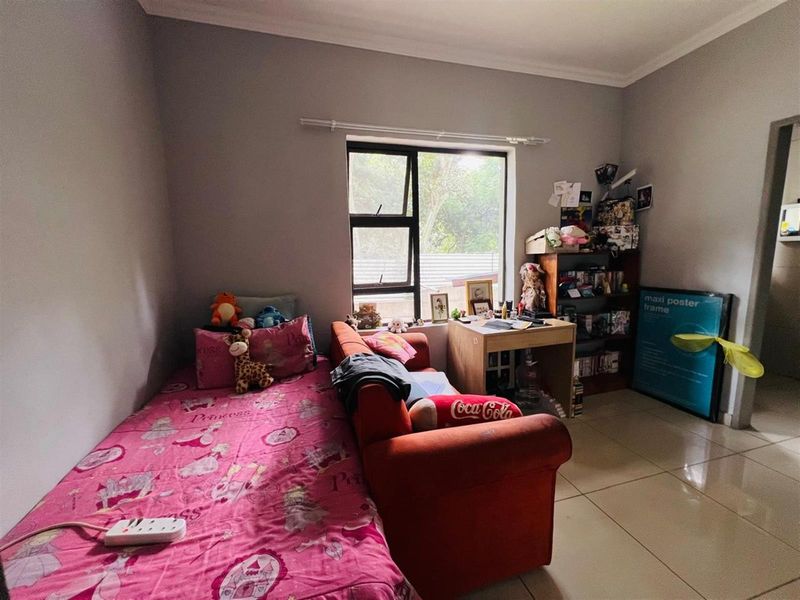 A bedroom featuring tiled flooring, neutral wall paint, and a window providing natural light.