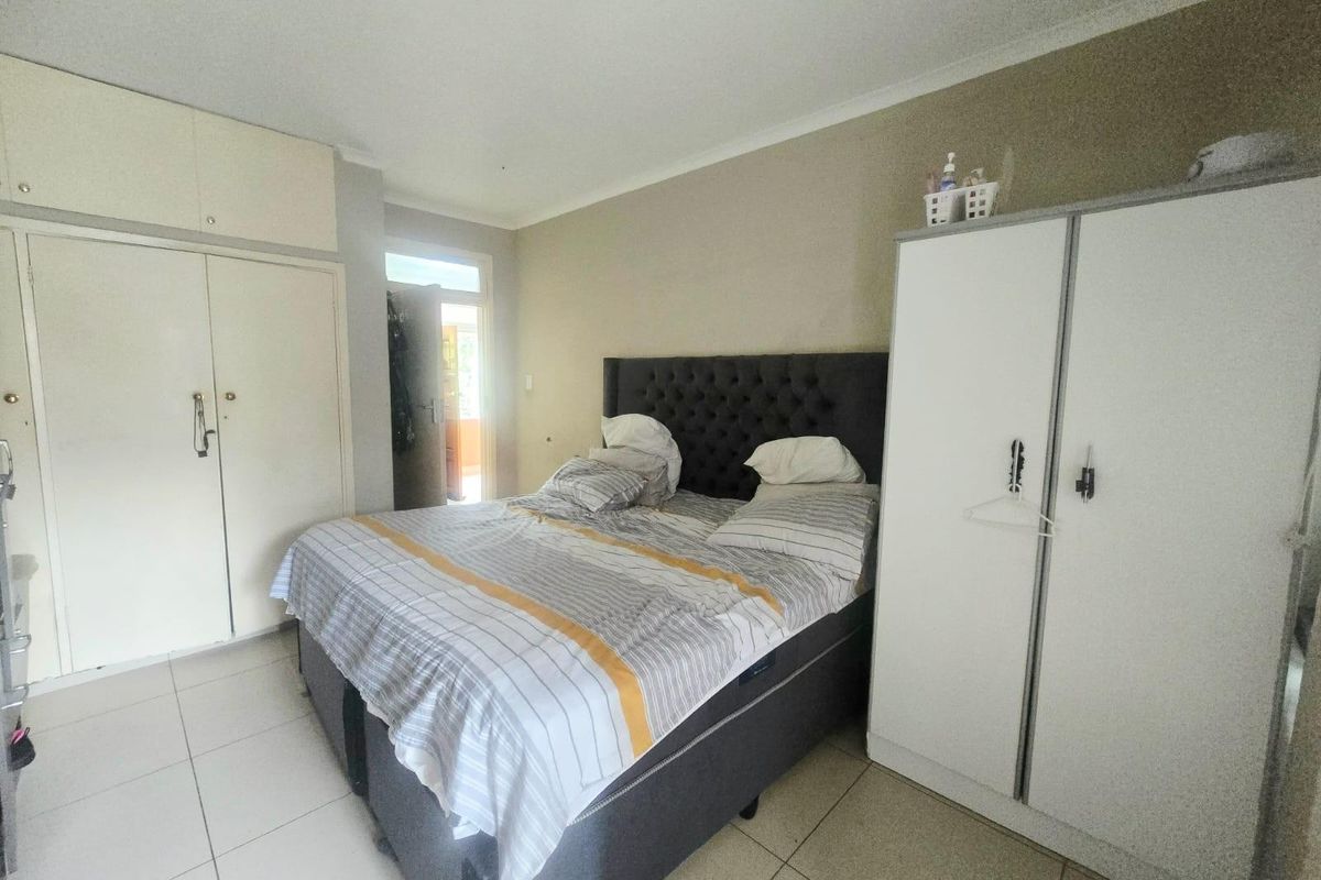 A functional bedroom featuring tiled flooring, built-in cupboards, and direct access to an outdoor area.