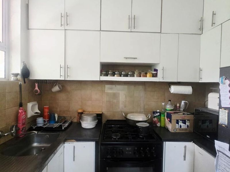Compact kitchen featuring white cabinetry, a gas stove with oven, stainless steel sink, and tiled backsplash.