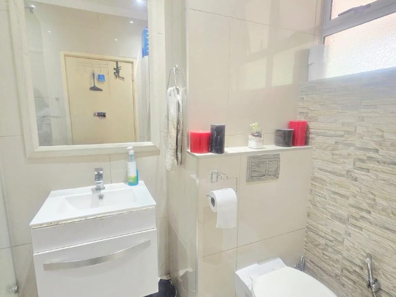 Modern bathroom featuring a wall-mounted vanity, basin, concealed cistern toilet with flush plate, and a decorative stone-clad feature wall.